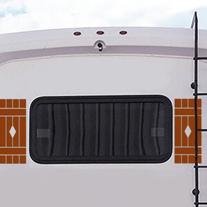 May include: A white RV exterior with a black window and decorative brown shutters. A black ladder is on the right side. The shutters have a diamond-shaped design in the center.