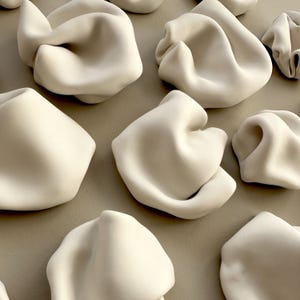 detail of abstract ceramic artwork, showing the flowing undulating forms, like ripples in water or the curves of a human form.