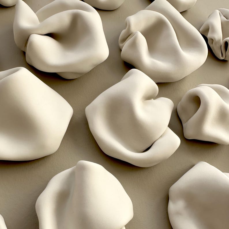 detail of abstract ceramic artwork, showing the flowing undulating forms, like ripples in water or the curves of a human form.