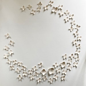 Circular arrangement of geometric flowers. Each piece has four points and is smooth in texture. They are arranged organically in a semi circle.