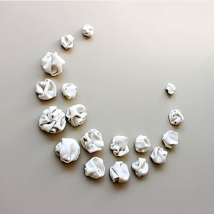 Set of 18 ceramic sculptures arranged in a crescent moon shape. Each individual piece is a unique creation featuring lots of curves and folds that have formed naturally when the clay has been warped in my hands.
