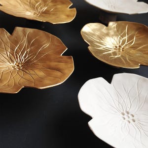 Side view of ceramic flowers and close up of imprinted detail in the centre. In the middle of each flower there are 9 imprinted dots and etched lines that spread out from the middle.