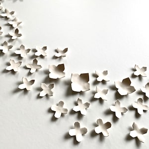 Original ceramic wall art shown slightly from the side. Designed for interior decoration wall art decor.
Each piece has four points, some with sharper points and some with curved edges.