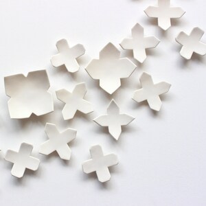 Close up of original ceramic wall art organically scattered from the left towards to right hand side. The full set is made up of 60 pieces and is designed for interior decoration. The set can be arranged in a number of ways.