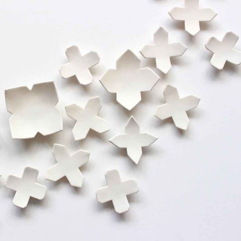 Close up of original ceramic wall art organically scattered from the left towards to right hand side. The full set is made up of 60 pieces and is designed for interior decoration. The set can be arranged in a number of ways.