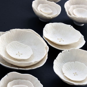 Close up of white porcelain abstract formations. Each piece has been delicately crafted by hand and designed to look like poppies and roses. With layers of porcelain to look like petals. Each layer of ceramic has an intricate and delicate texture.