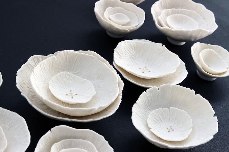 Close up of white porcelain abstract formations. Each piece has been delicately crafted by hand and designed to look like poppies and roses. With layers of porcelain to look like petals. Each layer of ceramic has an intricate and delicate texture.