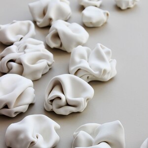 Close up and side view of the original ceramic sculptures. Each sculpture is handcrafted here in my studio. Each piece is different and unique. They consist of folded clay to create natural forms with curves.