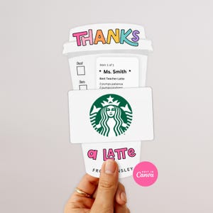 Op de afbeelding: Een witte papieren cadeaukaarthouder in de vorm van een koffiekopje met de woorden "THANKS" in kleurrijke letters. De cadeaukaarthouder heeft een Starbucks-logo en de woorden "a LATTE" en "Ms. Smith" erop gedrukt.