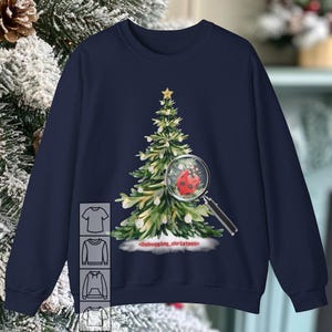 Può includere: Una felpa blu navy con un design a forma di albero di Natale. L'albero è decorato con luci bianche e una coccinella rossa è nascosta tra i rami. Il testo "<debugging_christmas>" è stampato sotto l'albero.