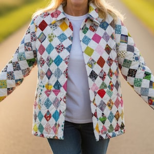 Puede incluir: Chaqueta acolchada con un patrón de diamantes en varios colores, usada sobre una camiseta blanca y vaqueros azules. El diseño de la chaqueta es un patchwork de diferentes telas, con colores como rojo, azul y amarillo.