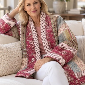 Puede incluir: Una chaqueta acolchada con diseño de patchwork que presenta varios patrones florales y geométricos en tonos rosa intenso, azul apagado y crema. La chaqueta tiene mangas largas, frente abierto y un cuello ancho con un estampado pequeño.
