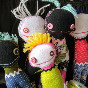 K&ouml;nnte beinhalten: F&uuml;nf handgefertigte Filzpuppen mit verschiedenen Haarfarben und Kleidung. Die Puppen haben Knopfaugen und gen&auml;hte L&auml;cheln.