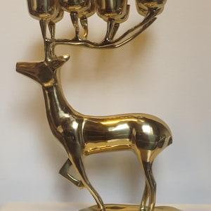 Peut inclure: Un bougeoir doré en forme de cerf avec quatre coupelles à bougies sur ses bois. Le cerf est debout sur une base ronde, une patte levée. Le bougeoir en métal a une finition polie et est un objet décoratif.
