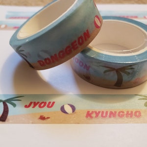 May include: Two rolls of blue and white patterned washi tape with red text. The text on the top roll reads "Donggeon" and the text on the bottom roll reads "Jyou Kyungho".