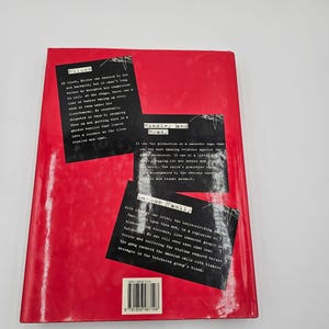 May include: A red book with black text and white text blocks. The text blocks contain excerpts about crime and violence. The book's title is not visible. The book has a barcode on the bottom left corner.