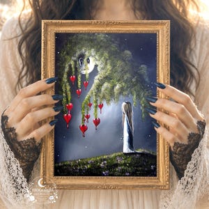 Puede incluir: Un cuadro enmarcado en un marco de tono dorado que representa una figura de pie sobre una colina cubierta de hierba bajo un gran &aacute;rbol llor&oacute;n. Las ramas del &aacute;rbol tienen corazones rojos colgantes que parecen gotear. El fondo es un cielo nocturno estrellado.