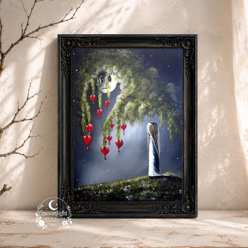 Puede incluir: Un cuadro enmarcado que representa una figura de pie sobre una colina cubierta de hierba bajo un gran &aacute;rbol oscuro con adornos rojos en forma de coraz&oacute;n. La escena se sit&uacute;a sobre un fondo oscuro y estrellado con un rostro lunar p&aacute;lido.