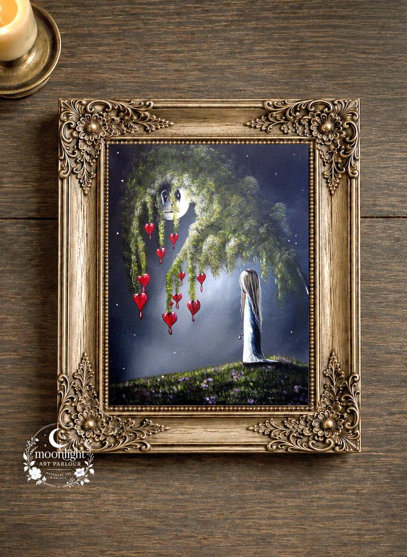Puede incluir: Una pintura enmarcada en un marco dorado ornamentado representa una figura de cabello largo de pie sobre una colina cubierta de hierba bajo un gran &aacute;rbol frondoso. Adornos rojos en forma de coraz&oacute;n cuelgan de las ramas contra un cielo nocturno estrellado. El texto Moonlight Art Parlour es visible en la esquina inferior izquierda.