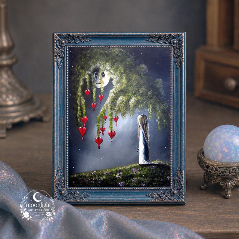 Puede incluir: Una pintura enmarcada en un marco azul oscuro ornamentado que muestra una figura de pie sobre una colina cubierta de hierba bajo un gran &aacute;rbol con adornos rojos en forma de coraz&oacute;n. La escena se desarrolla bajo un cielo nocturno con luna.