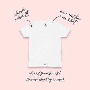 May include: A white t-shirt with a classic unisex fit, wear and tear resistant. The shirt has a small graphic on the back and text that says "oh and pre-shrunk! (because shrinking is rude)" on a pink background.