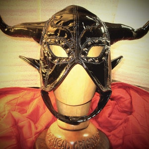 May include: Black leather mask with horns and silver studs. The mask has a pointed shape and covers the entire head.