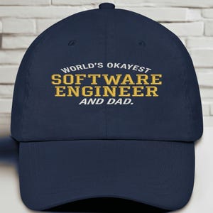 Peut inclure: Casquette de baseball bleu marine avec le texte brodé "WORLD'S OKAYEST SOFTWARE ENGINEER AND DAD" en or et blanc. La casquette a une visière incurvée et un bouton sur le dessus. Fabriqué en tissu durable.