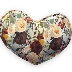 May include: A heart-shaped pillow with a floral pattern featuring red, white, and brown roses on a light blue background.