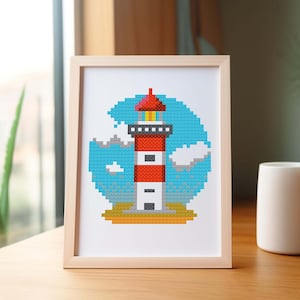 Könnte beinhalten: Ein gerahmter Pixel-Kunstdruck eines roten und weißen Leuchtturms mit blauem Himmel und weißen Wolken. Der Leuchtturm steht auf einem gelben Sandstrand.
