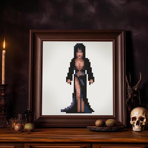 Könnte beinhalten: Ein gerahmter Pixel-Kunstdruck einer Frau in einem schwarzen Kleid und mit langen schwarzen Haaren. Der Druck ist vor einem dunklen Hintergrund mit Kerzen und anderen Dekorationsgegenständen platziert.