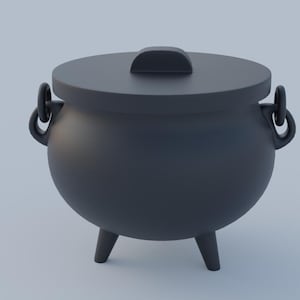 Puede incluir: Un caldero negro con tapa y tres patas. El caldero tiene dos asas a los lados.