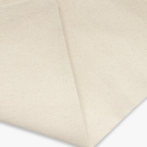 A blank canvas tote bag with flat corners and sturdy handles. Made of durable cotton in a natural color, it's perfect for carrying everyday items. A blank cotton canvas tote bag with sturdy handles.