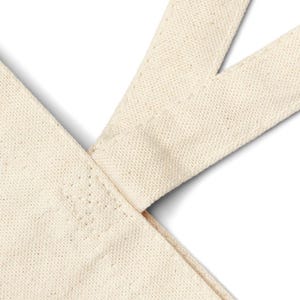 A blank, off-white canvas tote bag with reinforced handles for extra durability, the bag is made from durable cotton fabric in a natural, off-white color. The bag is spacious with a flat, sturdy bottom. Stitching from Chic Canvas Totes