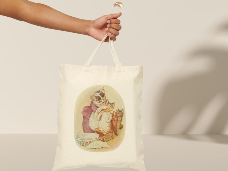 Mama Bag Tabitha Twitchit Tote Featuring Tom Kitten and Miss Moppet Cotton Canvas Tote Bag."Beatrix Potter Tabitha Twitchit Tote Bag featuring a vintage-style illustration of Tabitha Twitchit, the beloved mother cat from Tom Kitten’s story. Eco-friendly cotton tote with sturdy handles, perfect for book lovers, nursery decor, or everyday use. A charming gift for Beatrix Potter fans and collectors: Study handle