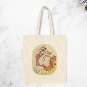 Mama Bag Tabitha Twitchit Tote Featuring Tom Kitten and Miss Moppet Cotton Canvas Tote Bag."Beatrix Potter Tabitha Twitchit Tote Bag featuring a vintage-style illustration of Tabitha Twitchit, the beloved mother cat from Tom Kitten’s story. Eco-friendly cotton tote with sturdy handles, perfect for book lovers, nursery decor, or everyday use. A charming gift for Beatrix Potter fans and collectors: front art image