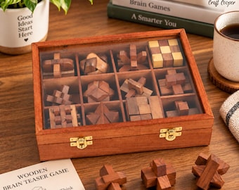 May include: A rectangular wooden box with a clear lid containing twelve distinct wooden brain teaser puzzles. Three additional wooden puzzles sit outside the box. A paper instruction card labeled Wooden Brain Teaser Game is included.