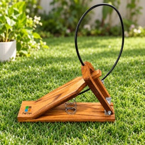 Puede incluir: Una herramienta de madera accionada por pedal con base articulada, un resorte metálico central y un gran bucle de alambre negro circular que se extiende hacia arriba. La madera tiene un acabado veteado natural y el logo Craft Cooper.