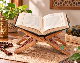 May include: A wooden book stand with intricate carved floral patterns holding an open book with white pages and black text. The stand features a folding X-shaped design crafted from light brown wood, providing a stable base for reading.