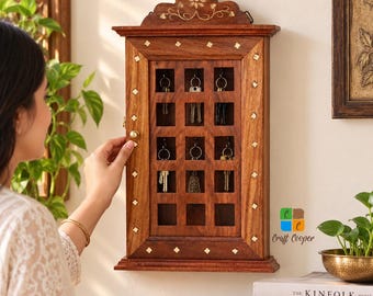 May include: A rectangular wall-mounted wooden key cabinet with a dark brown finish, featuring a grid of twelve open compartments, each equipped with a metal hook for hanging keys. The frame is decorated with small, inlaid diamond-shaped brass accents.
