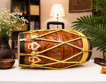 May include: A barrel-shaped dholak drum featuring a polished brown wooden body with carved textures, a black carrying handle, and yellow rope tensioning. The drum includes gold-toned metal hardware with heart-shaped accents and white drumheads.