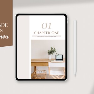May include: A digital tablet displaying a chapter one page of a digital planner. The page is white with brown text that reads "01 Chapter One" and "Your chapter title to be placed here". The background image is a photo of a wooden desk with a laptop, a white chair, a vase with greenery, and a wicker basket.