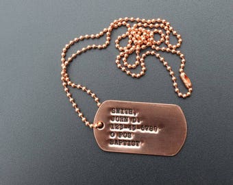 May include: A copper dog tag necklace with a ball chain. The tag is engraved with the text "SMITH, JOHN D. 123-45-6789 O POS BAPTIST".