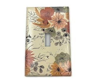 May include: A light switch cover with a floral pattern. The design features a variety of flowers in shades of orange, pink, and gray on a cream background.