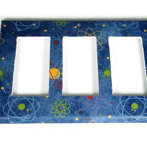 May include: A blue and white triple light switch cover with a retro atomic design. The cover features a repeating pattern of colorful atoms on a blue background.