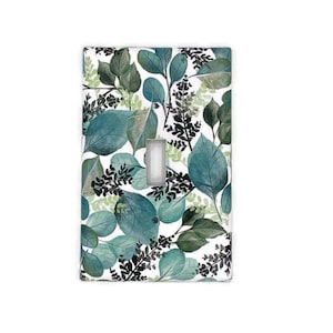 May include: A rectangular light switch cover featuring a watercolor design of green and blue leaves on a white background. The leaves vary in size and shape, with a central rectangular switch opening.