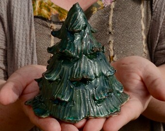 Op de afbeelding: Een handgemaakte kerstboomversiering van keramiek in een diepe groene glazuur. De boom heeft een textuur, een rustieke uitstraling en is perfect om een ​​toets van handgemaakte charme toe te voegen aan uw kerstdecoratie.