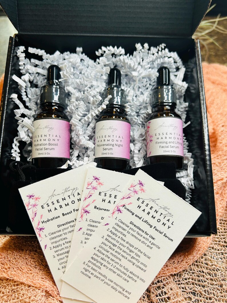 May include: A skincare gift set featuring three glass dropper bottles of facial serum, each labeled with "Essential Harmony." The set includes cards with instructions. The bottles are in a black box with white paper filler.