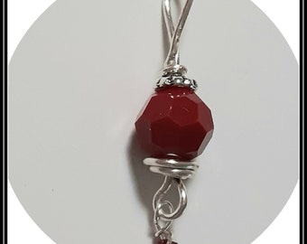 May include: A silver wire wrapped pendant with a red faceted glass bead and a small red crystal dangle.