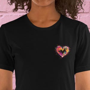 Könnte beinhalten: Schwarzes T-Shirt mit einem bunten Herzdesign auf der linken Brust.