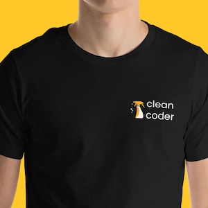 Könnte beinhalten: Schwarzes T-Shirt mit einer kleinen Grafik einer Sprühflasche und den Worten "clean coder" in Weiß. Die Sprühflasche ist gelb und weiß. Das T-Shirt hat einen Rundhalsausschnitt.